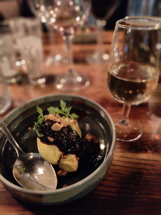 Gourmetdessert med sås, glass och strössel, serveras med vin, intim atmosfär, restaurang eller middag.