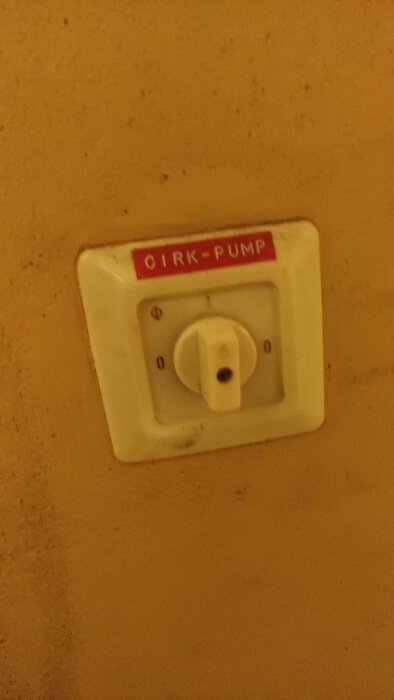 En smutsig strömbrytare märkt "CIRK-PUMP" med på/av-läge på en vägg.