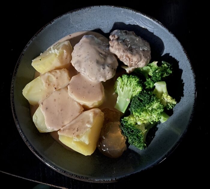 En tallrik med köttbullar, potatis, brunsås och broccoli. Enkel hemlagad måltid.