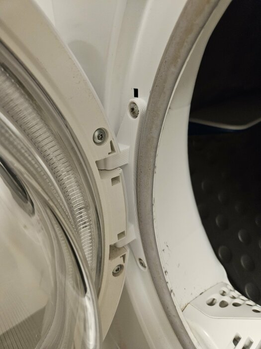 Närbild på en tvättmaskins öppning med fokus på tätningen och låshaken.