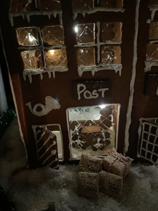 Pepparkakshus med posttema, ljus i fönster, istappar, paket framför. Vinterkänsla, detaljrik, handgjord dekoration.