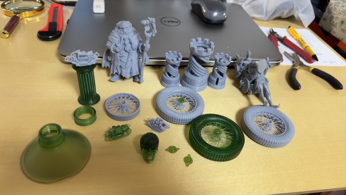 3D-utskrivna objekt, figurer, verktyg, cykeldelar och gröna plastdelar på ett skrivbord.