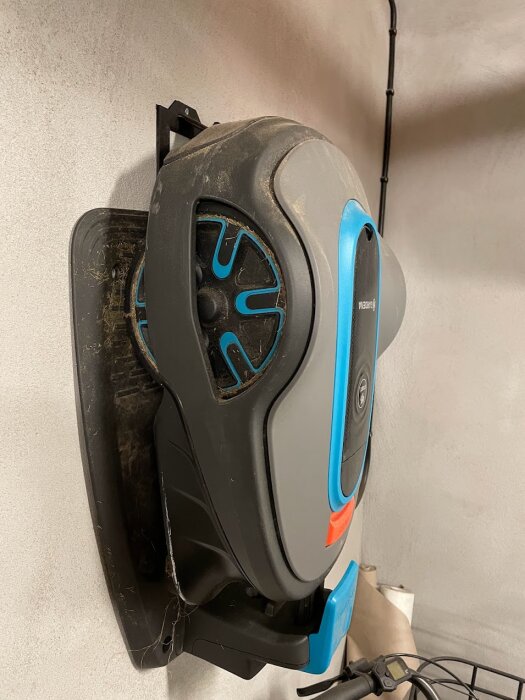 En smutsig elektrisk enhjuling hänger på en väggmonterad hållare i ett rum.