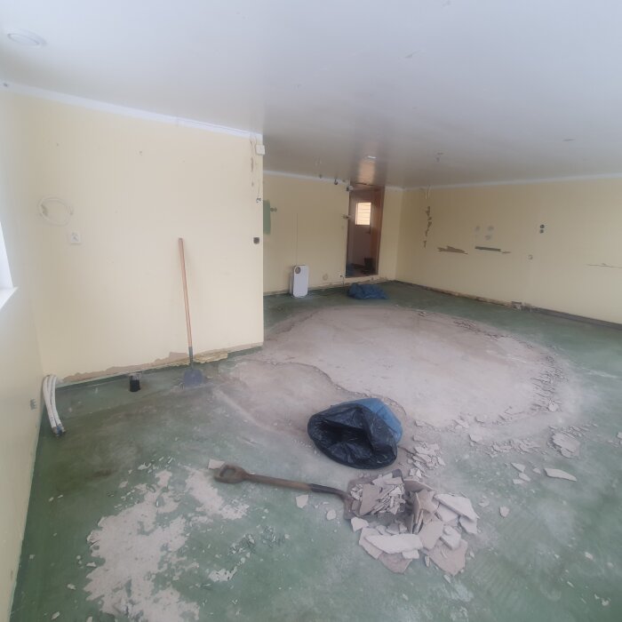 Tomrum under renovering, golv utan beläggning, spackelspadar, skräp, kabeldragning synlig på väggar.