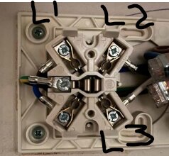 Elektrisk dosa med kablar anslutna till skruvklämmor, märkta med L1, L2, L3.
