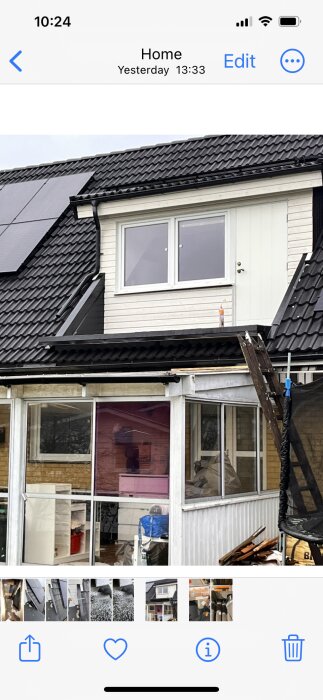 Husfasad, tak med solpaneler, fönster, byggnadsställning, skräp, del av mobilgränssnitt.