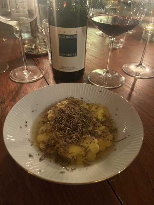 Gnocchi med tryffel, vinflaska, vinglas, middagsmiljö, träbord, intim atmosfär.