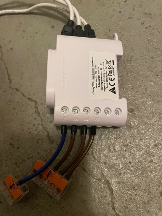 Elapparat med ledningar och WAGO-kopplingar på betong. Teknisk etikett synlig. Elektrisk installation.