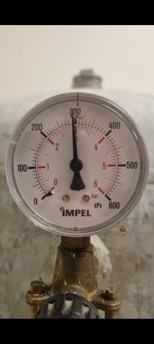 Manometer med skala i bar och kPa, monterad på rör, dammig, möjligen industriell miljö.