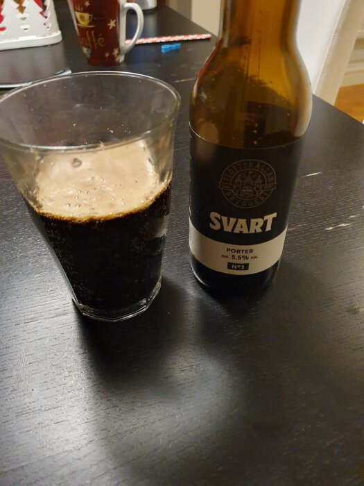 Ett glas mörkt öl och en ölflaska märkt "SVART PORTER" på ett bord.