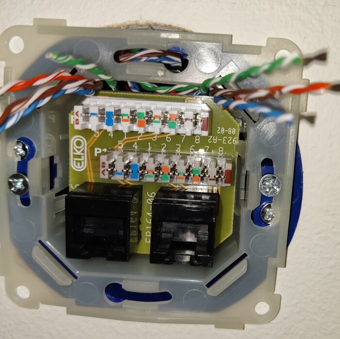 En nätverksdosa för Ethernet-kabelanslutning med osammanhängda kablar och kretskort synliga.
