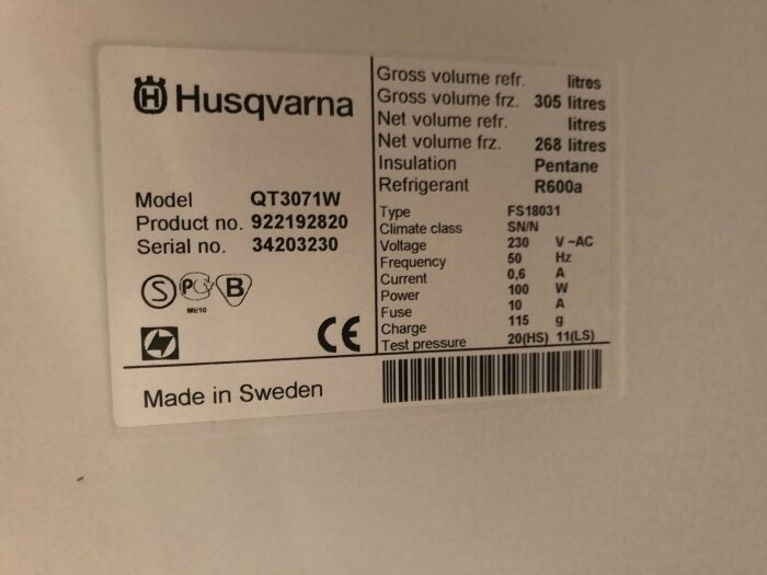 Etikett från Husqvarna för apparat, specificerar modell, serienummer, kapacitet, strömförbrukning, tillverkad i Sverige.