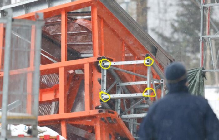 Röd konstruktionsställning, snöfall, fyra gula markeringar, person i förgrunden med ryggen vänd mot kameran.