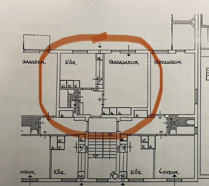 Arkitektonisk ritning av husplan, markerad med orange cirkel, innehåller kök, vardagsrum och sovrum.