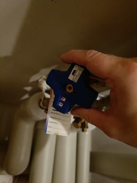 Hand håller blå ventil ovanför rör - Installationsarbete, underhåll eller reparation.