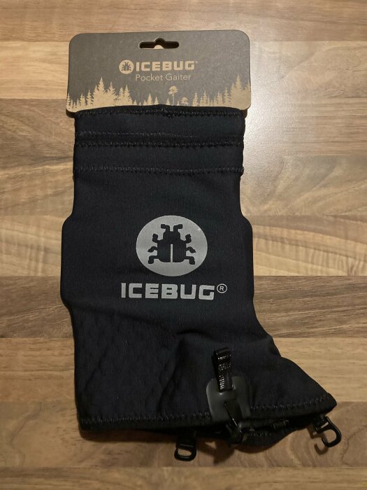 Svart ICEBUG Pocket Gaiter på träbakgrund, förpackning intakt, utomhusaktivitetstillbehör.