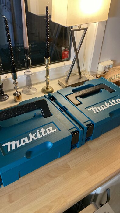 Blå Makita verktygslådor på bord, inredningsdetaljer, ljusstake, lampa, fönster reflektion.