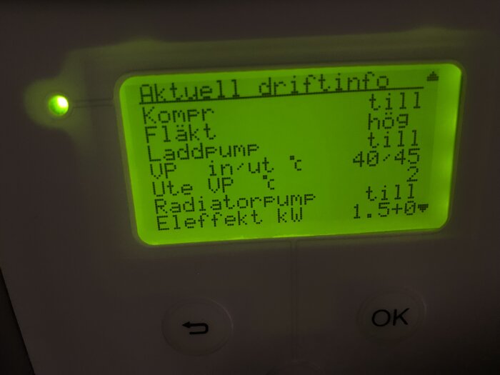 Digital display med driftinformation för värmesystem, grönt ljus, knappar, på svenska, bakgrundsbelysning.