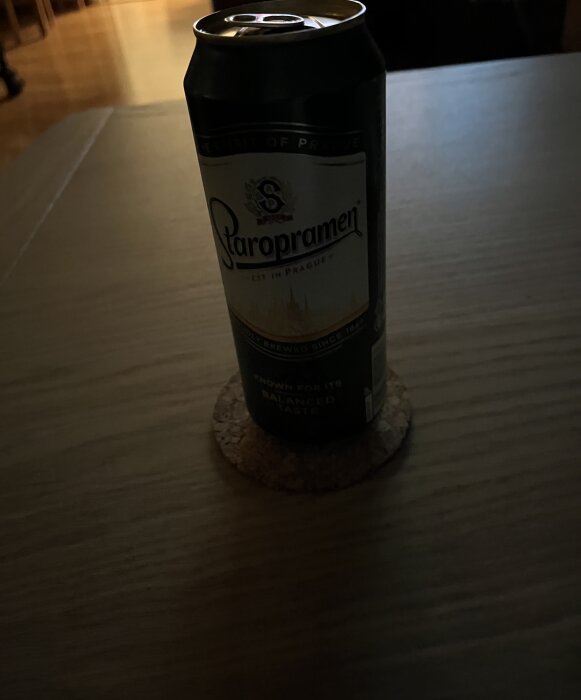 Staropramen ölburk på bord i dunkelt rum.