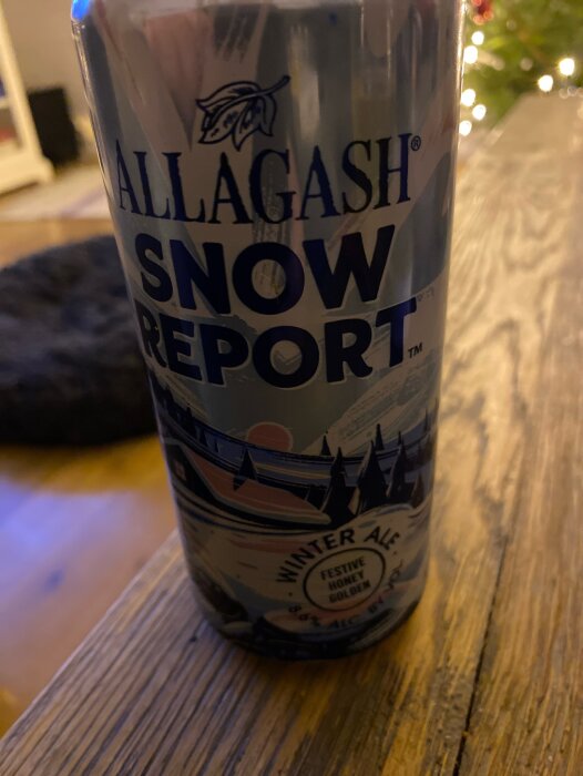 Allagash Snow Report vinteröl, honungsgulden, ölburk med julgranar och ljus i bakgrunden.