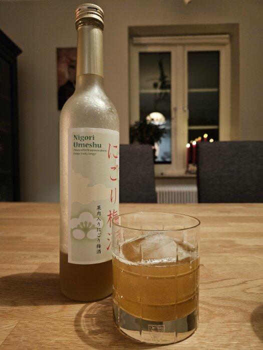 Flaska Nigori Umeshu, dryck med is i glas, inomhus, belysning, kväll, reflektioner, mysig atmosfär.