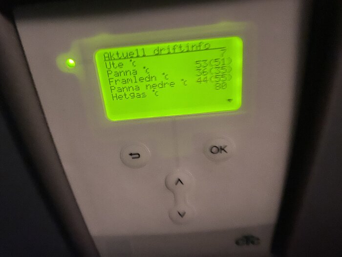 Digital display på en enhet, visar temperaturinformation, svensk text, suddig, knappar för navigering.