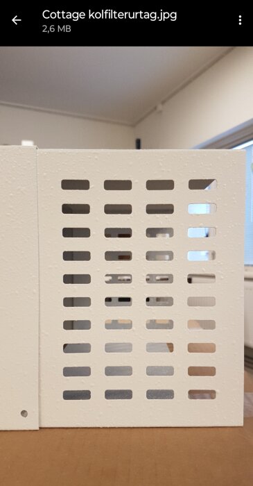Ventilationsspalter på en vit strukturerad vägg, inomhusmiljö, filnamn synligt i övre vänstra hörnet.