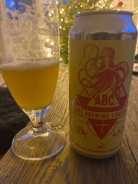 Ett glas öl bredvid ölburk från Apex Brewing Company, IPA 6.5%, julgran i bakgrunden.