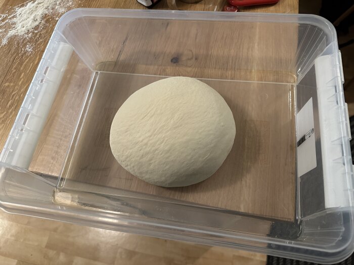 Degklump på träyta i genomskinlig plastlåda, förmodligen jäsningsprocess för bakning.
