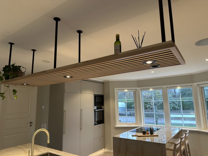 Modernt kök, flytande taklampa, trä och svart, minimalistisk design, stora fönster, ljus interiör.