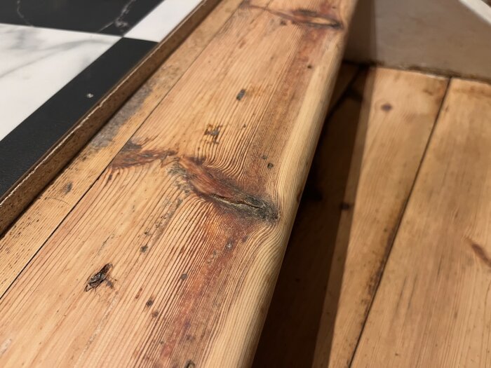 Träyta med ådring, mörknat märke, vid sidan en del av skrivblock.
