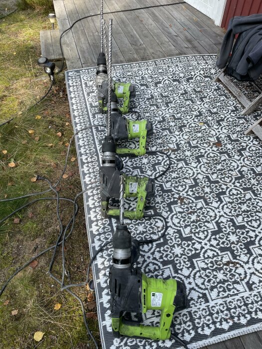 Flertal eldrivna verktyg på en matta utomhus, kabel och jacka i bakgrunden, arbete pågår möjligtvis.