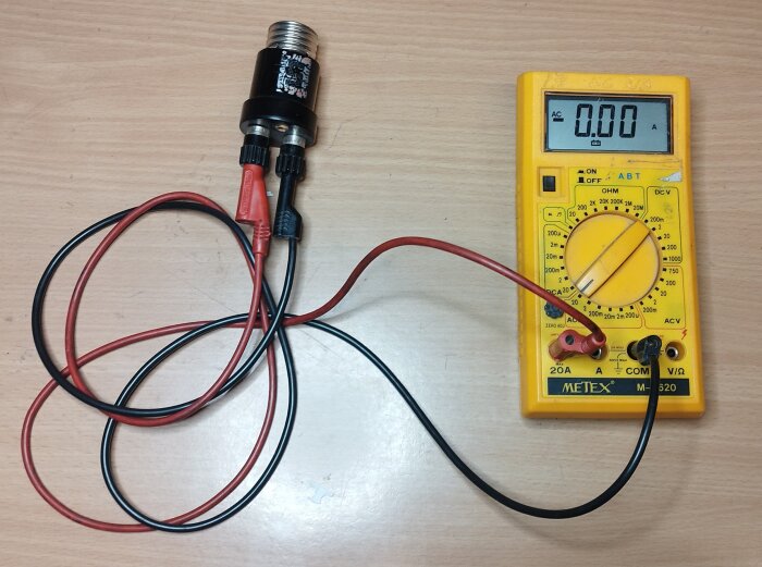 Elektrisk krets med multimeter och ansluten glödlampa på ett bord. Testingredienser för elektricitet.