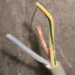 Avskalad elektrisk kabel med tre ledare: en blå neutral, en brun fas, och en oisolerad jordledning.