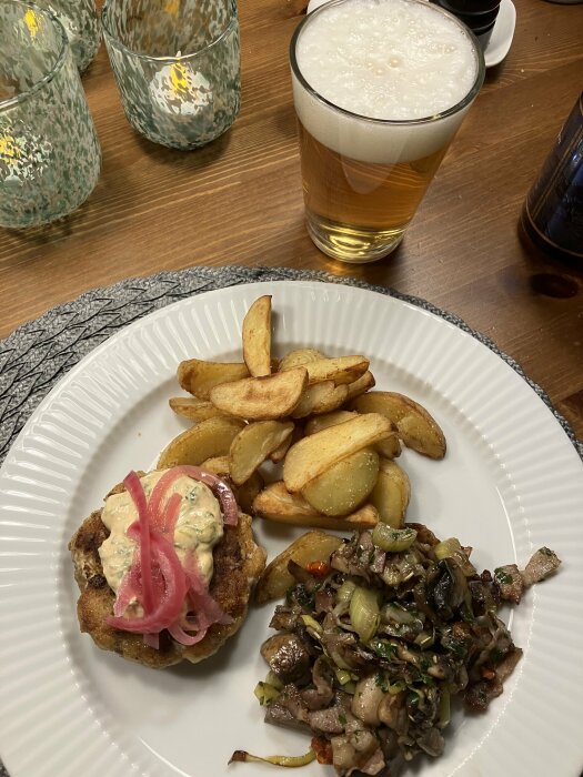 Måltid med kött, ugnsrostade potatisar, sallad, majonnäs, inlagda rödlökar och ett glas öl.