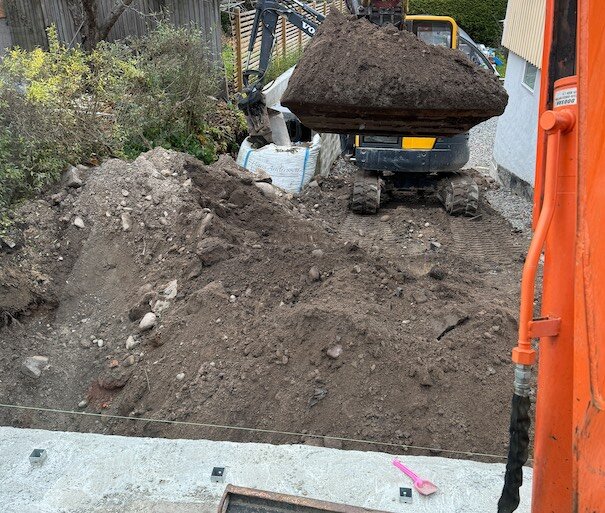 Byggarbetsplats med grävmaskin och dumper som flyttar jord; grävning pågår.
