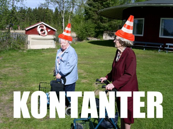 Två äldre damer med trafikkoner på huvudena, står på gräs, humoristisk bild, text "KONTANTER".