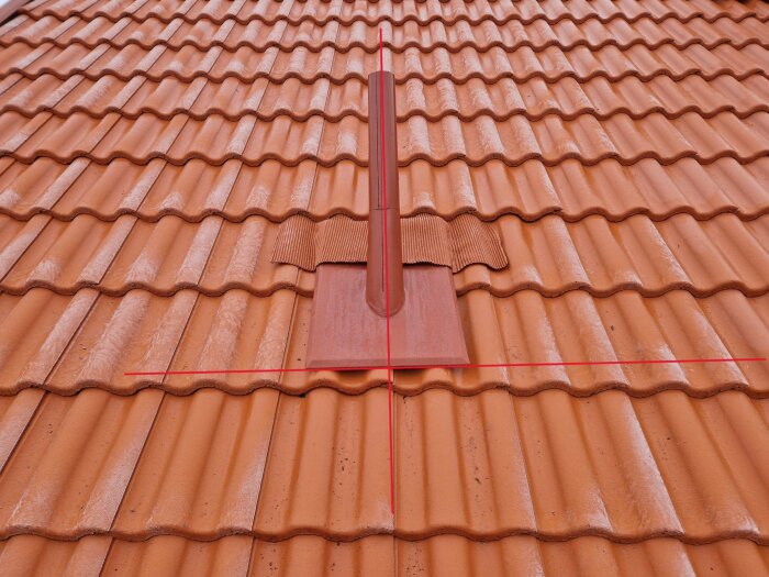 Tak med röda takpannor och en ventileringspanna, symmetriskt mönster, arkitektonisk detalj, hantverk.