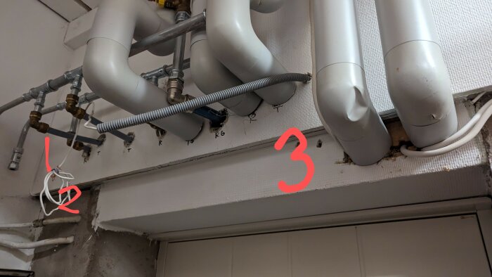Rörledningar under tak, märkta med siffror och kablar, installation i byggnad, vattensystem.