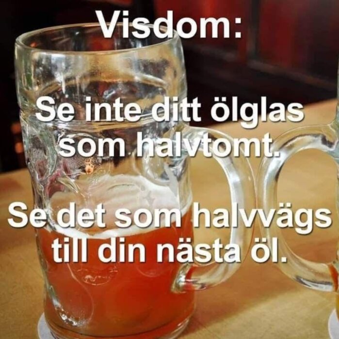 Ölglas halvfullt med text som föreslår positivt tänkande om nästa öl istället för tomhet. Humoristisk visdom.