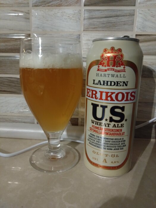 Ett glas öl bredvid en ölburk med texten "Hartwall Lahden Erikois US Wheat Ale".