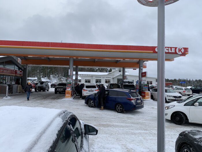 Circle K-bensinstation på vintern med snö, bilar och kunder.