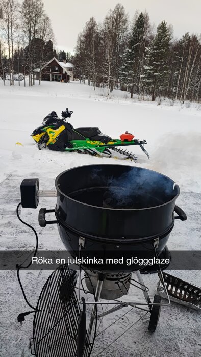 Rökning av julskinka utomhus i snön, med grill och snöskoter i bakgrunden.