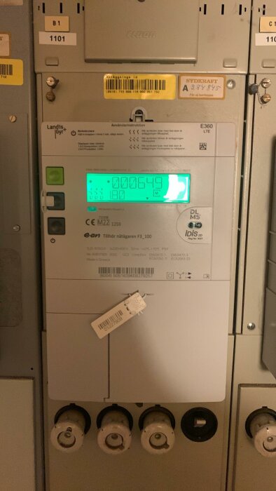 Elmätare med digital display, varningsetiketter och Siemens-logotyp i elrum.