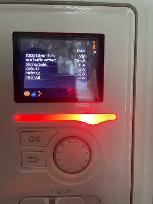 Elektronisk display visar teknisk data, troligtvis för en elanläggning, omringad av knappar och larmindikator.