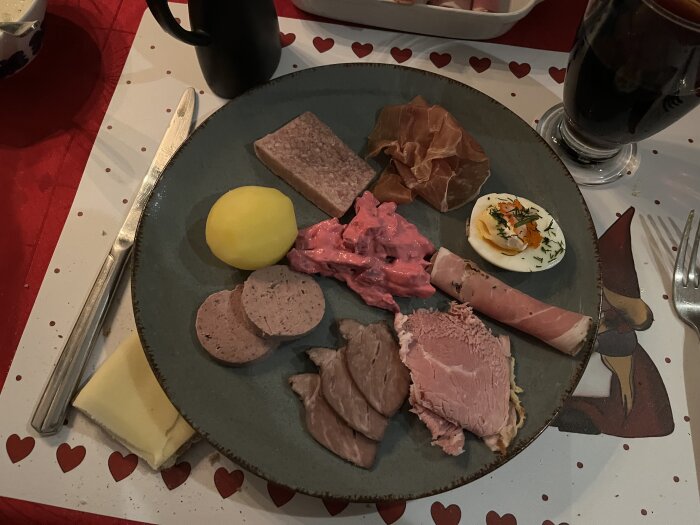 Ett julbord med blandade kallskuret: skinka, leverpastej, rödbetssallad, potatis, ägg, ost, korv.