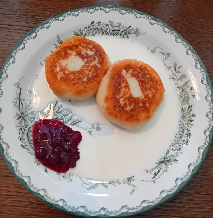 Två stekta bullar och sylt på dekorerad tallrik, enkel frukost eller fika.