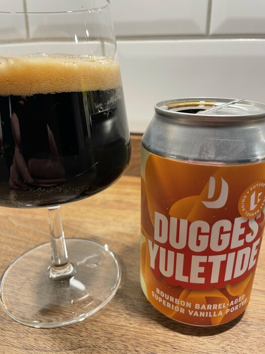 Ett glas med mörkt öl och en ölburk märkt "Dugges YULETIDE Bourbon Barrel-Aged Superior Vanilla Porter".