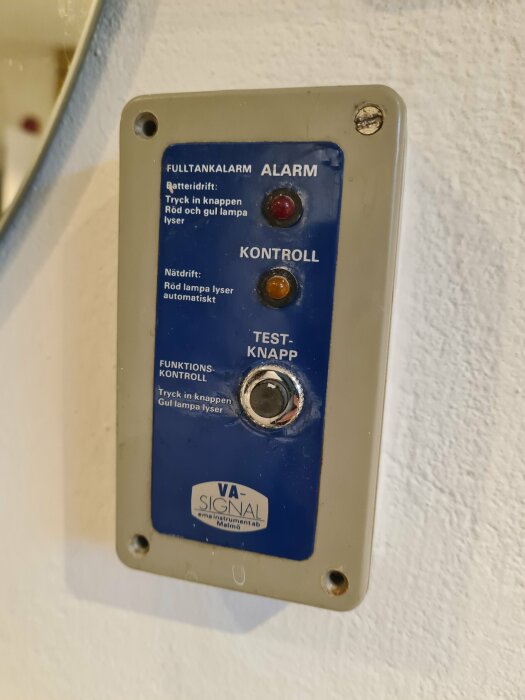 Kontrollpanel för fulltankalarm med tester och statuslampor, märkt "VA-SIGNAL", fastmonterad på vägg.