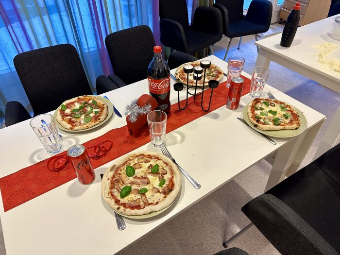 Tre hemlagade pizzor på bord, Cola, kryddställ, vattenglas, stolar, färgglada gardiner i bakgrunden.